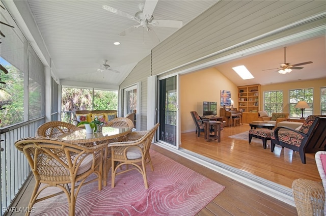 sunroom / solarium featuring lofted ceiling with skylight, plenty of natural light, and ceiling fan