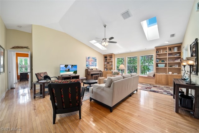 living room with ceiling fan, vaulted ceiling with skylight, and light wood-type flooring