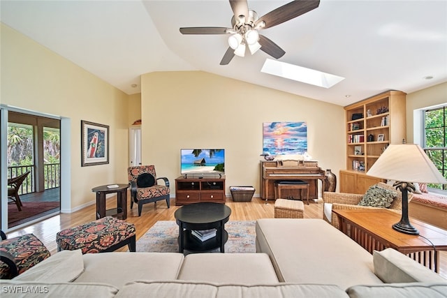 living room with vaulted ceiling with skylight, ceiling fan, and light hardwood / wood-style floors