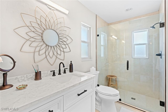 bathroom with a shower with door, vanity, and toilet