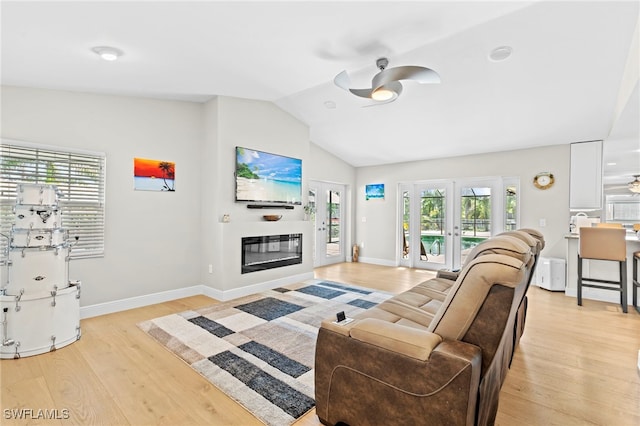 living room with ceiling fan, plenty of natural light, vaulted ceiling, and light hardwood / wood-style flooring