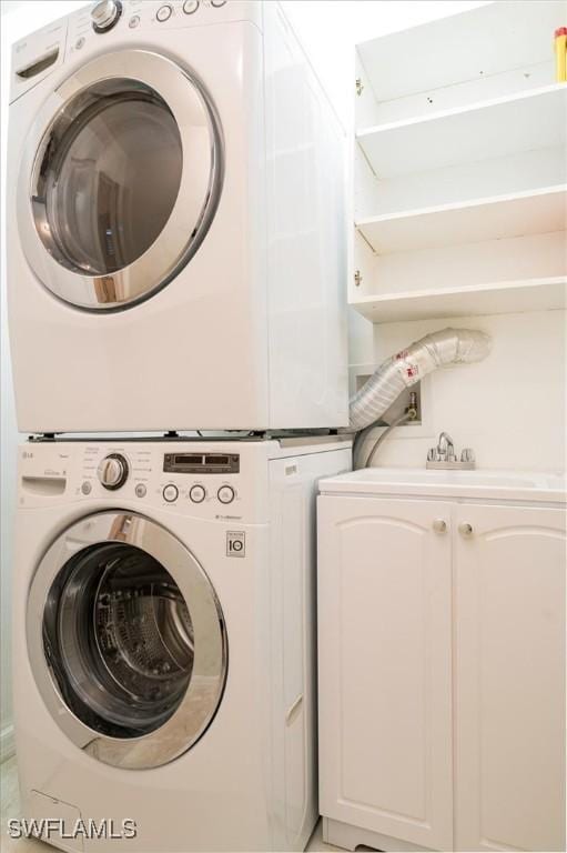 washroom featuring cabinets and stacked washer / drying machine