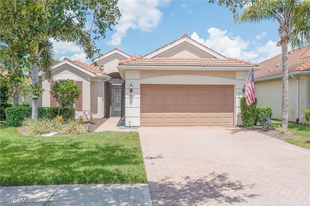 mediterranean / spanish-style home with a garage, decorative driveway, a tile roof, and stucco siding