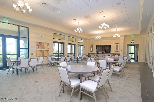 dining space with french doors, a towering ceiling, and an inviting chandelier