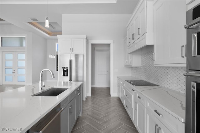 kitchen with light stone countertops, stainless steel appliances, sink, decorative light fixtures, and white cabinets