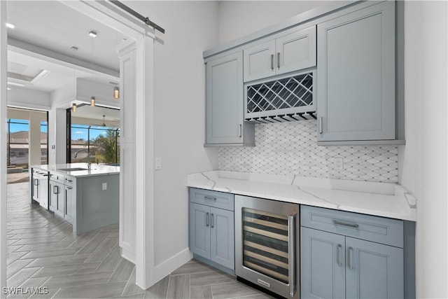 bar with sink, beverage cooler, a barn door, backsplash, and light parquet floors