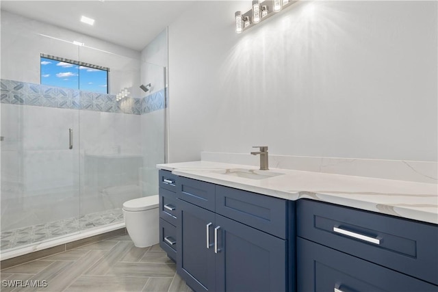 bathroom featuring vanity, toilet, and a shower with shower door