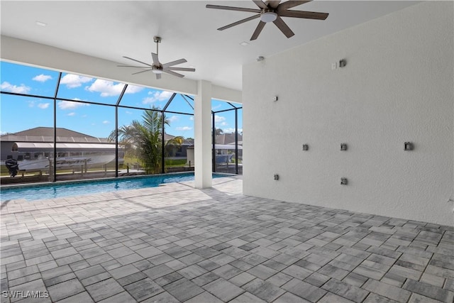 view of swimming pool featuring glass enclosure, ceiling fan, and a patio area