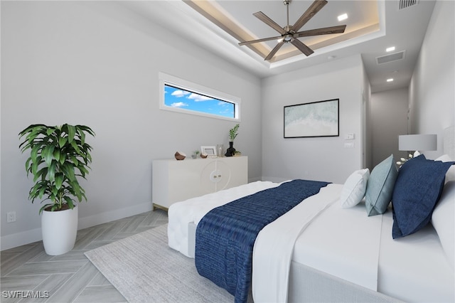 bedroom with a raised ceiling, light parquet floors, and ceiling fan