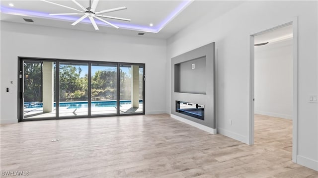 unfurnished living room featuring a tray ceiling and light hardwood / wood-style flooring