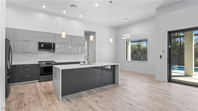 kitchen featuring appliances with stainless steel finishes, a towering ceiling, pendant lighting, sink, and gray cabinetry