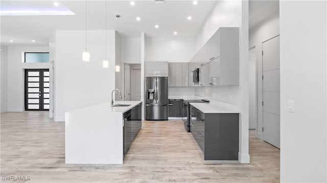 kitchen with sink, gray cabinets, hanging light fixtures, a high ceiling, and black appliances