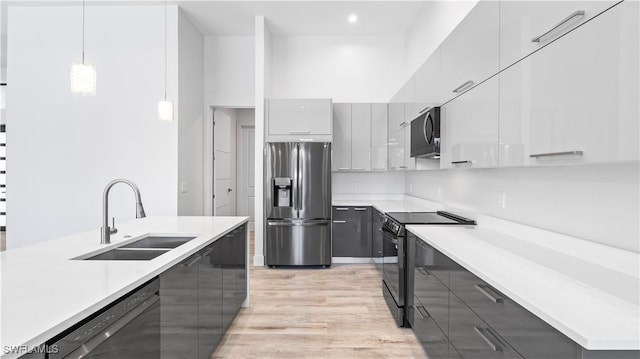 kitchen featuring sink, gray cabinetry, hanging light fixtures, light hardwood / wood-style floors, and black appliances