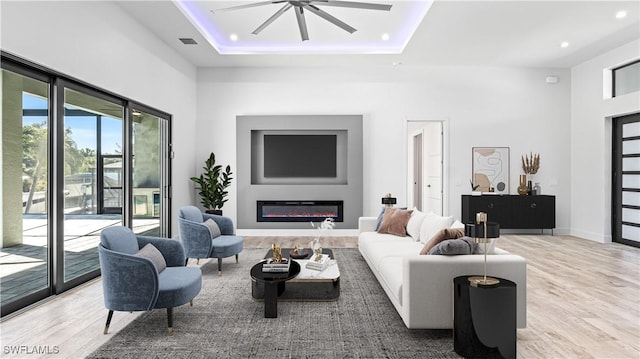 living room with a high ceiling, hardwood / wood-style floors, and a tray ceiling