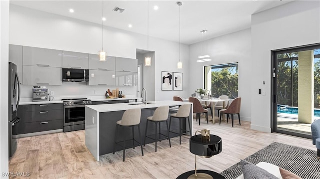 kitchen featuring gray cabinets, appliances with stainless steel finishes, pendant lighting, sink, and a high ceiling