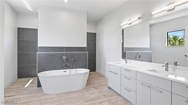 bathroom with vanity, a tub to relax in, and hardwood / wood-style flooring