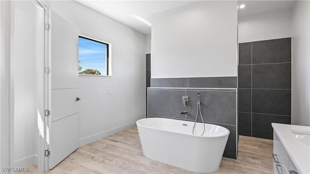 bathroom with vanity, a bath, and hardwood / wood-style floors