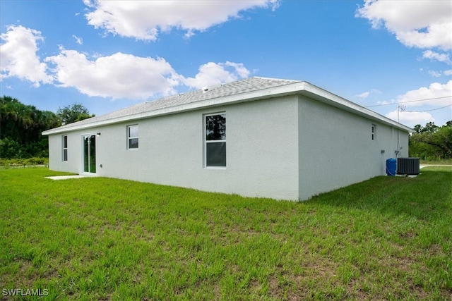 back of property with a lawn and central AC