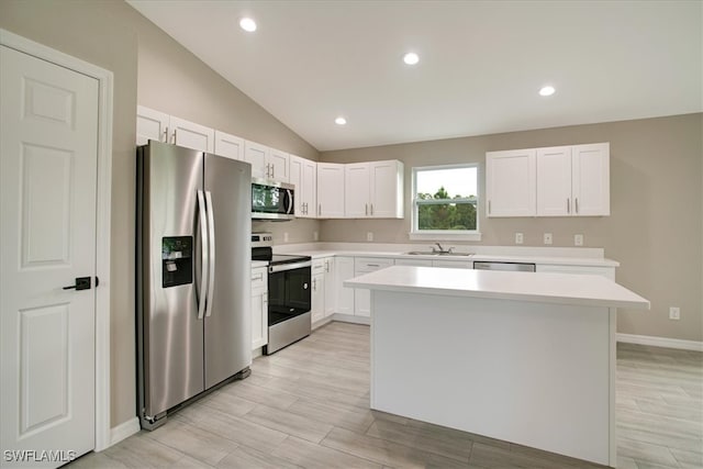 kitchen with appliances with stainless steel finishes, vaulted ceiling, sink, white cabinets, and a center island