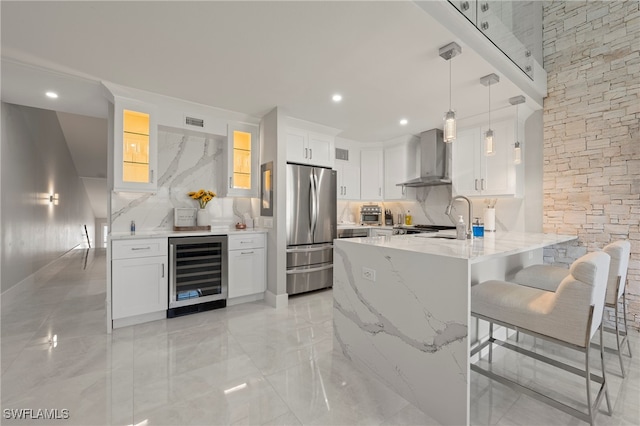 kitchen with backsplash, hanging light fixtures, stainless steel fridge, white cabinetry, and beverage cooler