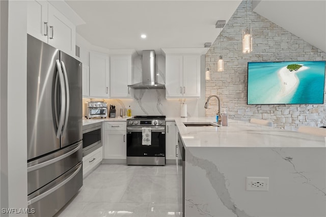 kitchen with light stone countertops, wall chimney exhaust hood, stainless steel appliances, sink, and white cabinets