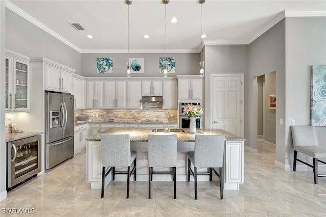 kitchen featuring white cabinets, stainless steel appliances, wine cooler, and a kitchen island with sink