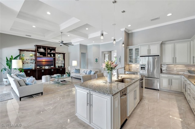 kitchen with tasteful backsplash, beamed ceiling, a center island with sink, white cabinets, and appliances with stainless steel finishes