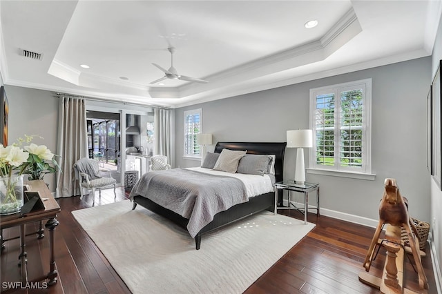 bedroom with dark hardwood / wood-style flooring, access to outside, ceiling fan, and a tray ceiling