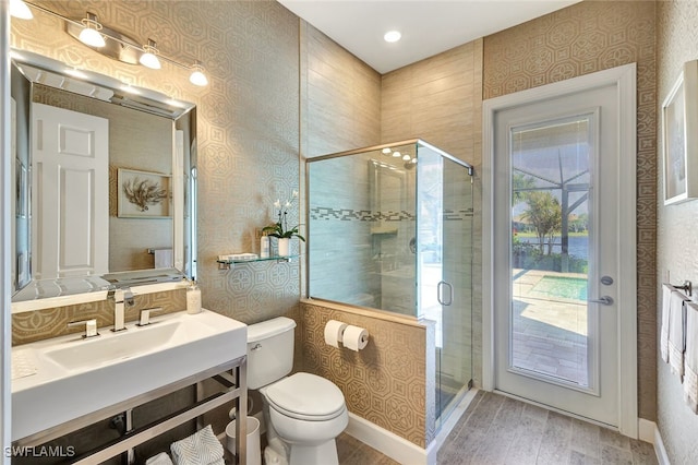 bathroom with wood-type flooring, vanity, toilet, and a shower with door