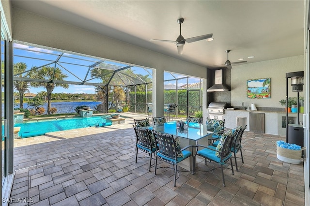 view of patio with grilling area, an outdoor kitchen, a water view, sink, and ceiling fan