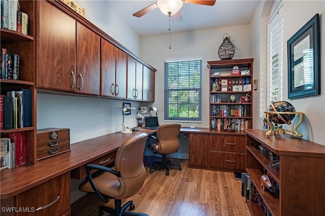 office space with ceiling fan, built in desk, and light hardwood / wood-style floors