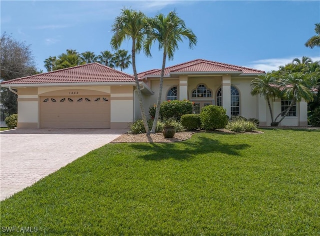 mediterranean / spanish-style home featuring a garage, a front lawn, decorative driveway, and stucco siding