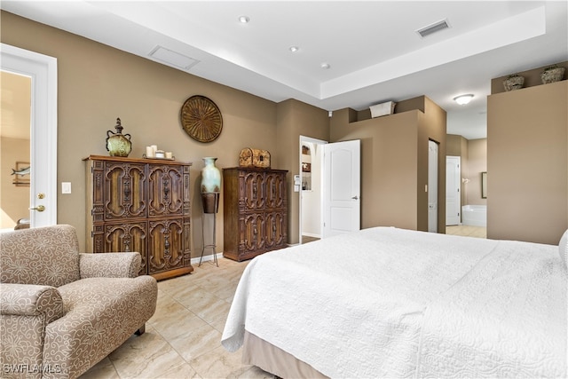 bedroom featuring light tile patterned floors, a tray ceiling, and ensuite bath