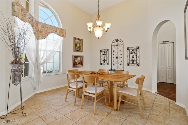 dining room featuring a healthy amount of sunlight, a high ceiling, and a notable chandelier