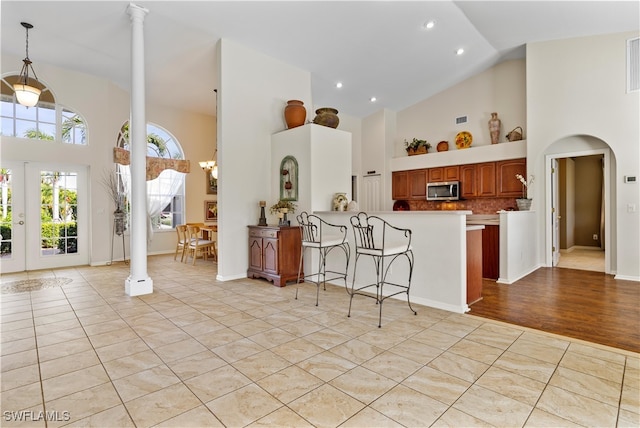 kitchen with pendant lighting, a kitchen breakfast bar, kitchen peninsula, and high vaulted ceiling