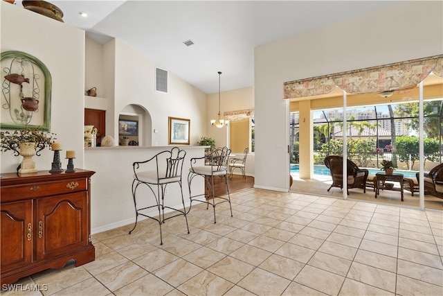 kitchen with light tile patterned floors, high vaulted ceiling, decorative light fixtures, and an inviting chandelier