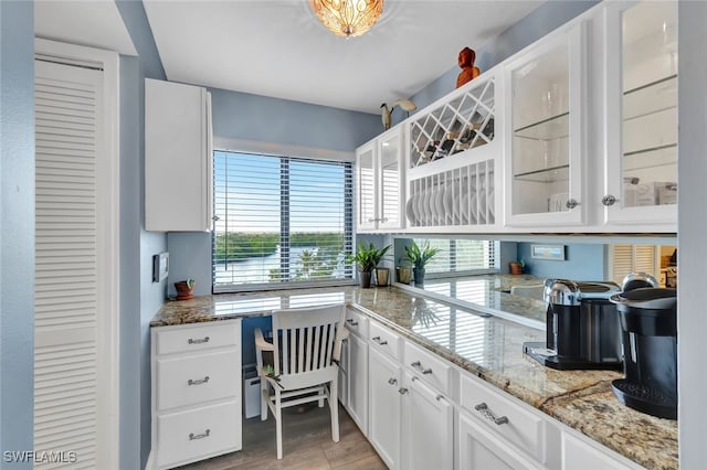 kitchen featuring white cabinets, light stone counters, and light hardwood / wood-style flooring