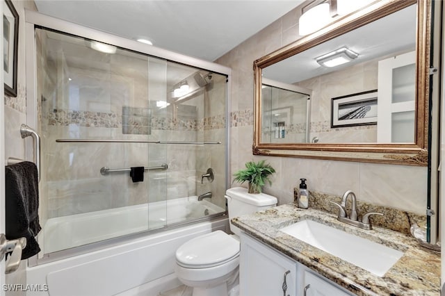 full bathroom with enclosed tub / shower combo, tile walls, vanity, and toilet