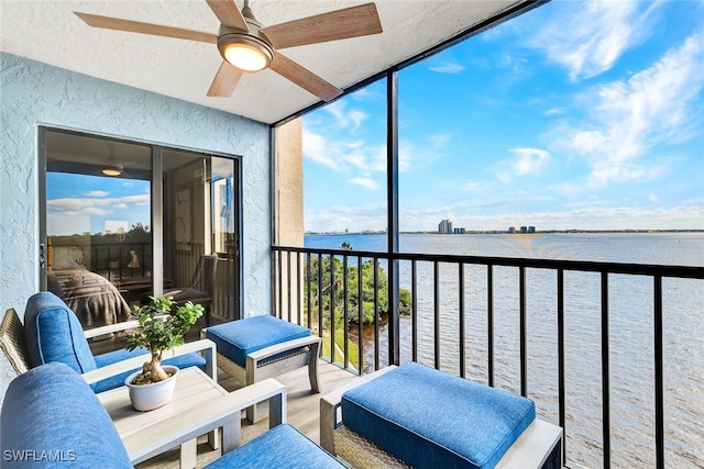 sunroom featuring ceiling fan and a water view