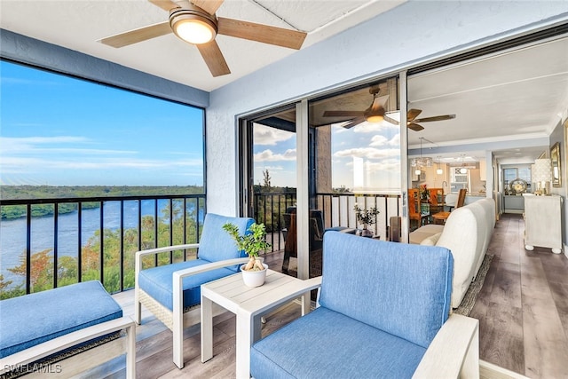 sunroom with ceiling fan and a water view