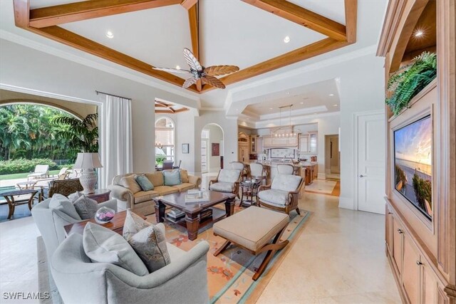 living room with ceiling fan, crown molding, a high ceiling, and a tray ceiling