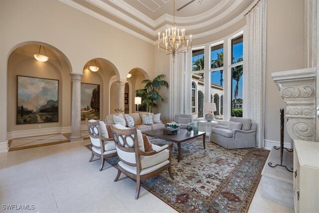 living room featuring a high ceiling, ornamental molding, a tray ceiling, a notable chandelier, and decorative columns