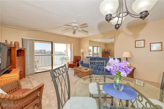 dining space featuring ceiling fan with notable chandelier, a textured ceiling, and light colored carpet