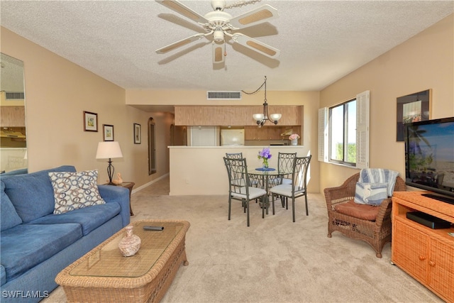 carpeted living room featuring ceiling fan with notable chandelier and a textured ceiling