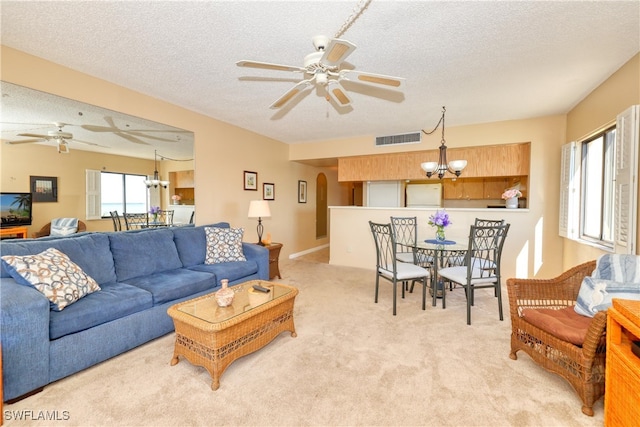 carpeted living room featuring ceiling fan with notable chandelier and a textured ceiling