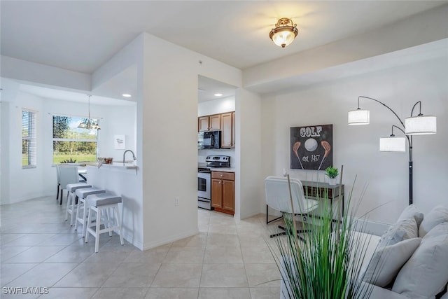 kitchen featuring light tile patterned floors, pendant lighting, stainless steel range with electric stovetop, and an inviting chandelier