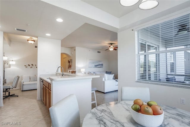 tiled dining area with ceiling fan and sink