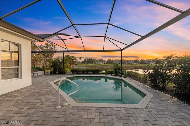 pool at dusk with a lanai, a water view, and a patio