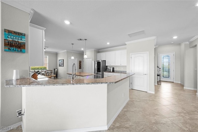 kitchen with white cabinets, stainless steel fridge, kitchen peninsula, and light stone countertops