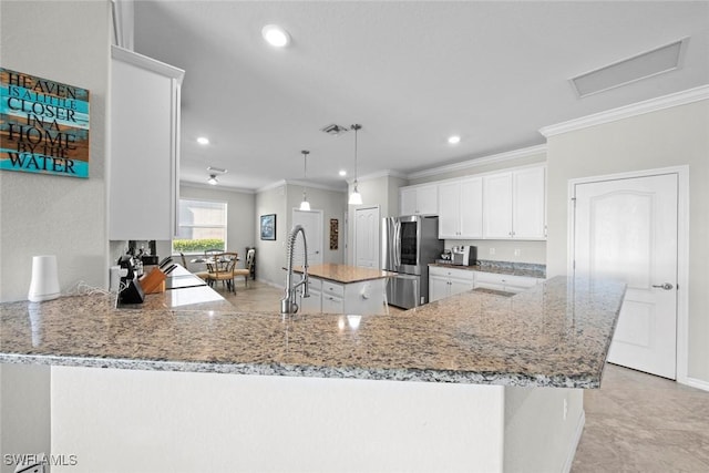 kitchen with white cabinetry, a center island, kitchen peninsula, stainless steel fridge, and pendant lighting